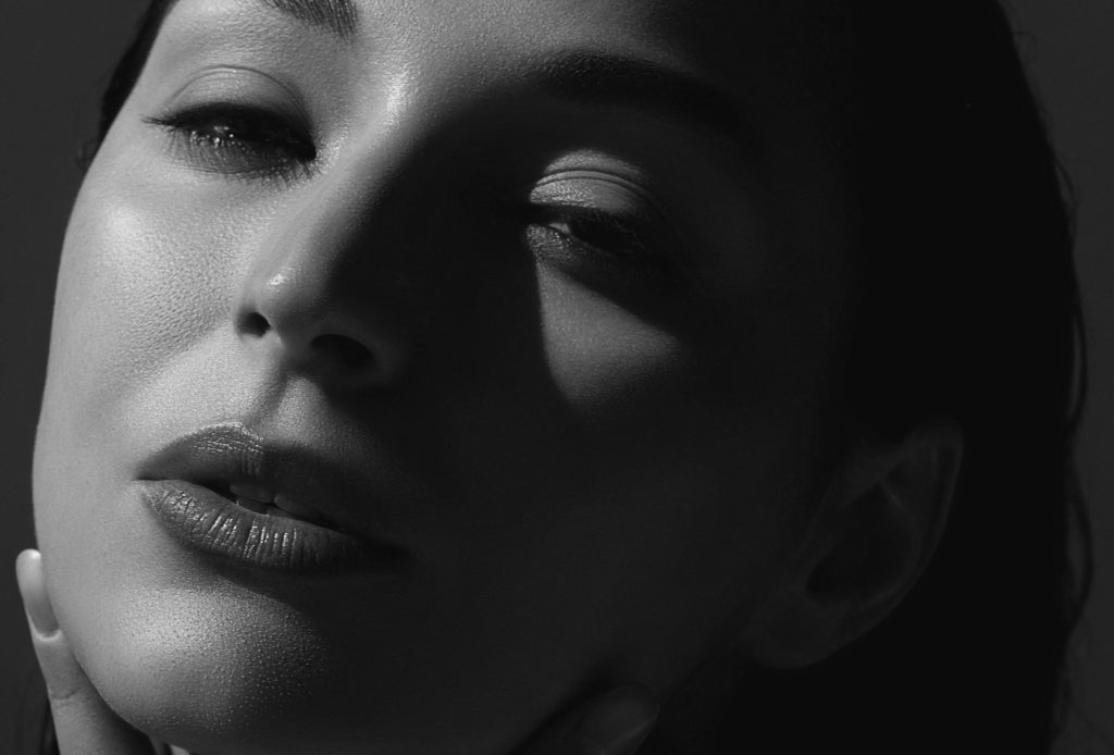 Closeup of woman's face with shadow on one side.